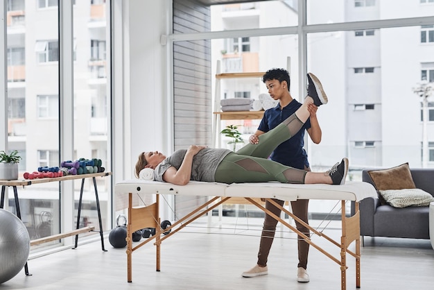 Youll be back on your feet in no time Full length shot of a young physiotherapist doing leg exercises with her patient inside her office at a clinic