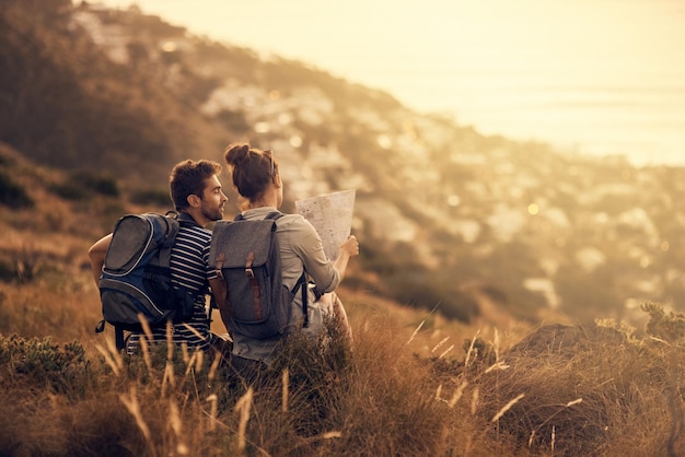 Youll never regret a day outdoors Rearview shot of a couple looking at a map while taking a break from hiking