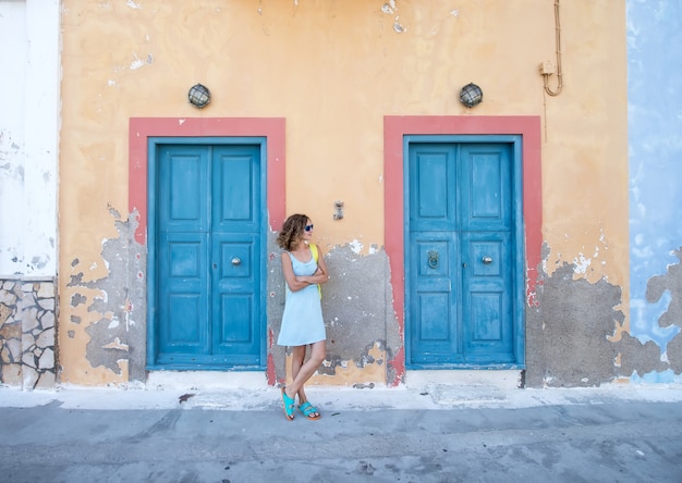 Yound blond woman at typical greek traditional town with colorful buildings on Kastelorizo Island, Greece