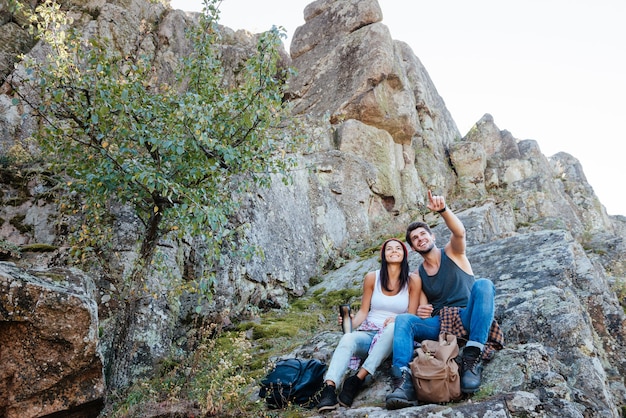 Young active couple enjoying view from top of a mountain and pointing finger