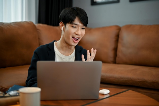 Young adorable Asian man having a video call with his family on laptop computer