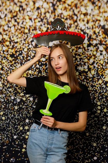 Young adorable girl holding board and standing on gilded background