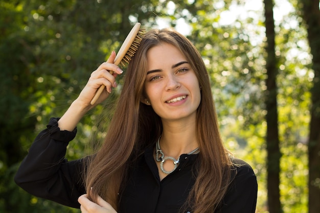 Young adoreable woman with long brown hair in black blouse and silver necklace standing back