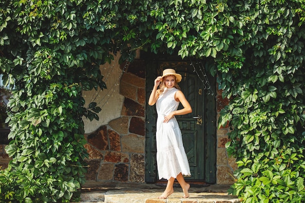 Young adult blonde in a white dress with apples on the hem in the garden at house