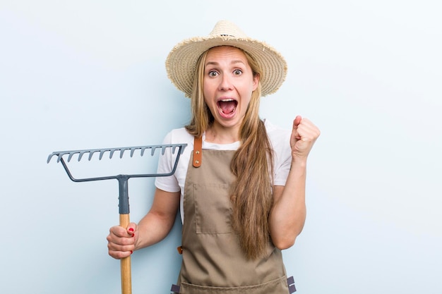 Young adult blonde woman farmer with a rake