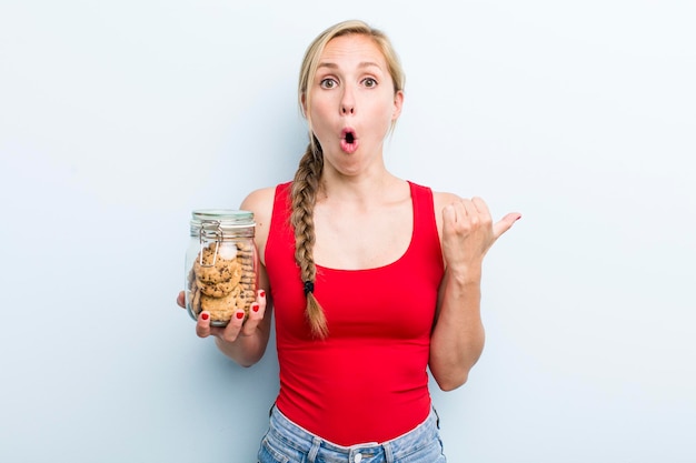 Young adult blonde woman with home made cookies bottle