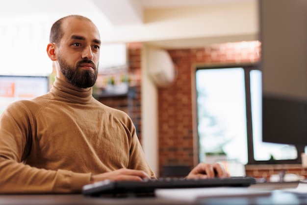 Young adult businessman analyzing budget reports while researching business plans. Fintech company project manager developing financial technology and marketing strategy while in office.