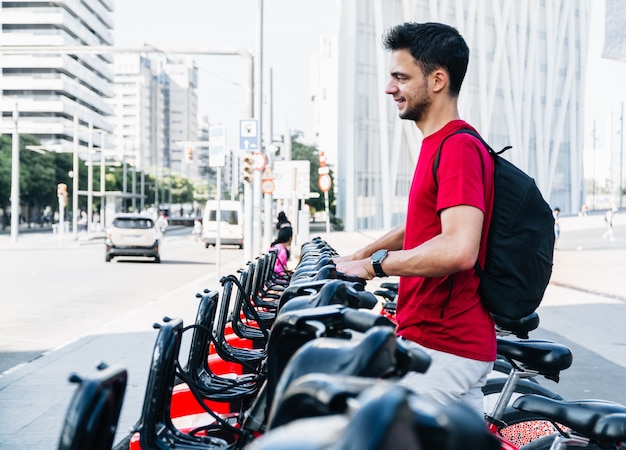 Young adult caucasian student taking a rented bicycle