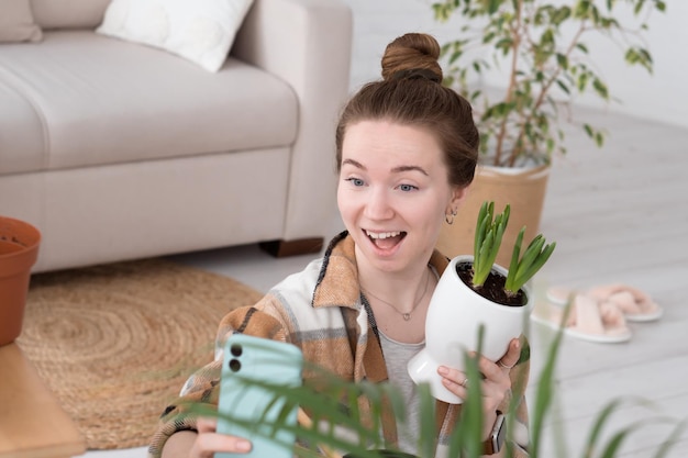 Young adult Caucasian woman doing selfie photo with houseplant after transplantation it to new pot