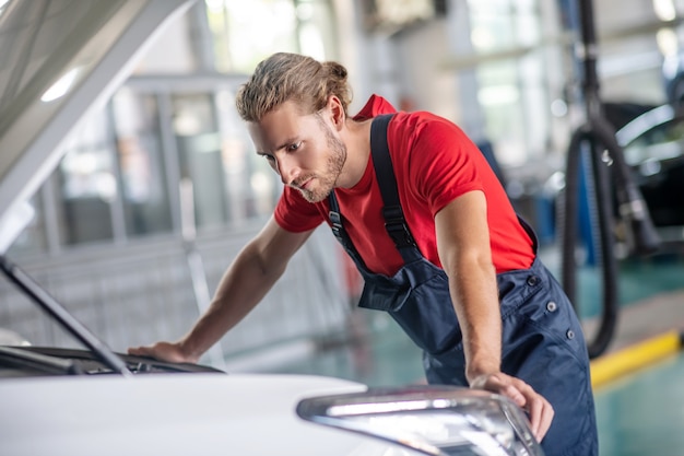 Young adult confident man in work uniform working on cars