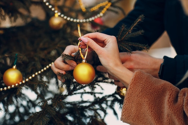 Young adult couple decorates christmas tree in winter forest. New year pine holiday party celebration concept.