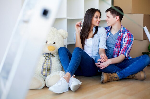 Young Adult Couple Inside Room with Boxes Holding New House Keys Banner