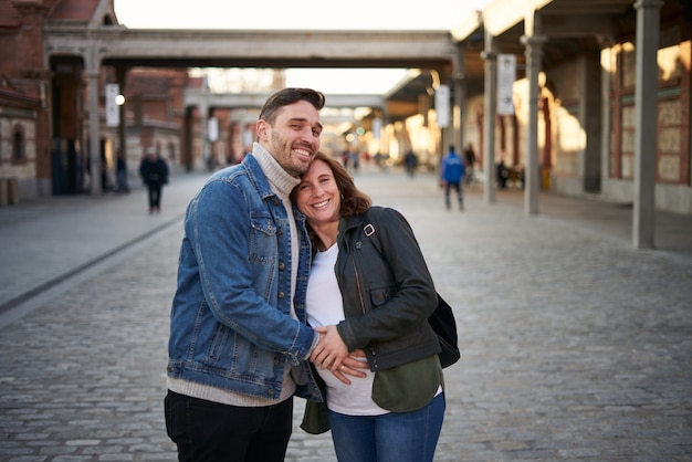 Young adult couple poses happily, pregnant woman.