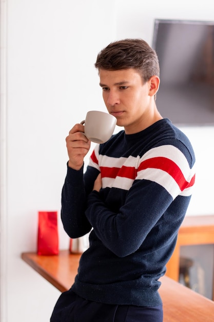 Young adult drinking a cup of coffee in the morning to start a day full of energy. Latin man.