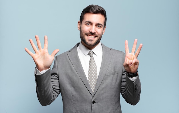 Photo young adult handsome businessman smiling and looking friendly, showing number eight or eighth with hand forward, counting down