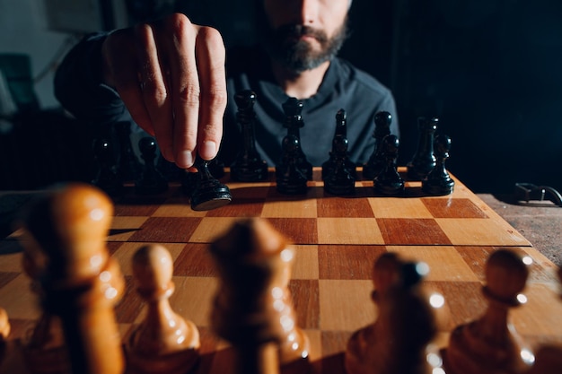 Young adult handsome man playing chess in dark with side lit