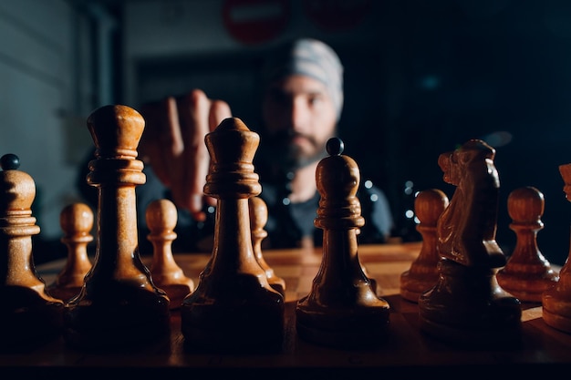 Young adult handsome man playing chess in dark with side lit