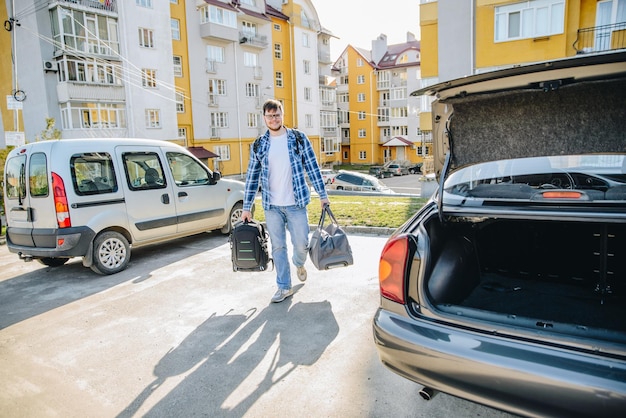 Young adult man putting bag in car trunk car travel concept