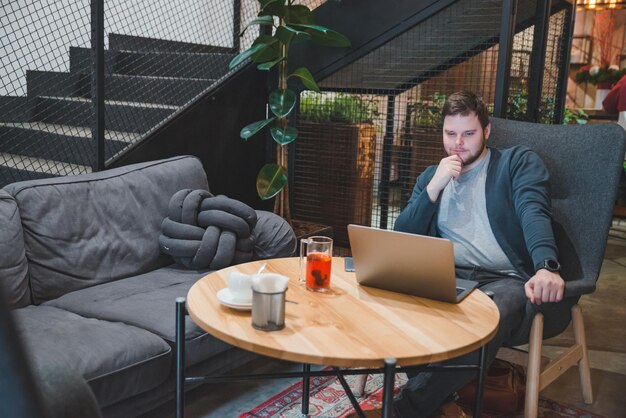 young adult man working on laptop in cafe drinking fruit tea freelance lifestyle