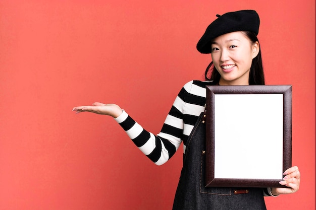 Young adult pretty asian woman with a beret and an empty picture frame