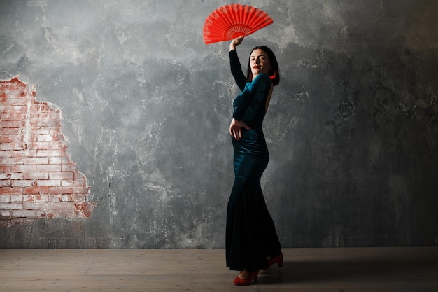 Young adult spanish woman dancing flamenco on gray vintage background