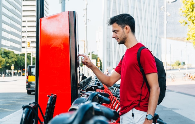 Young adult student renting a bicycle in a big city