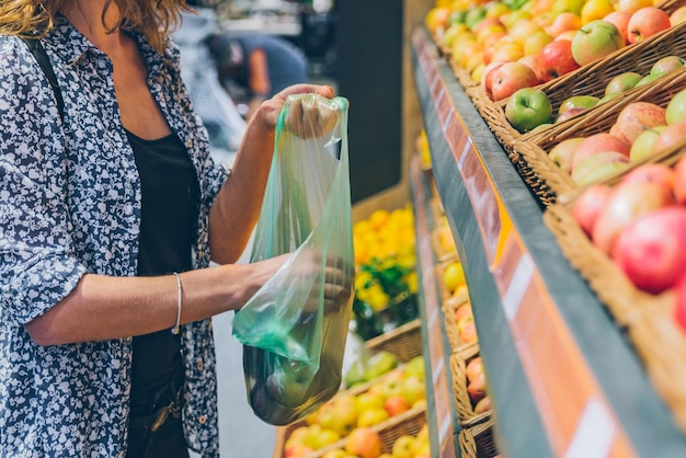 Young adult woman choosing apples in grocery store