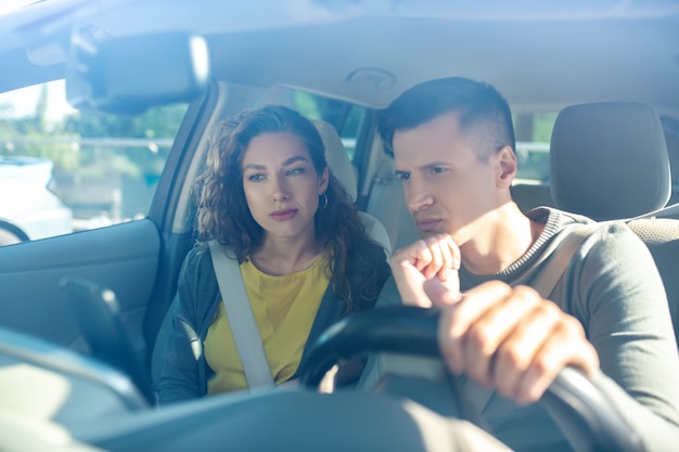 Young adult woman and man in interior of new car