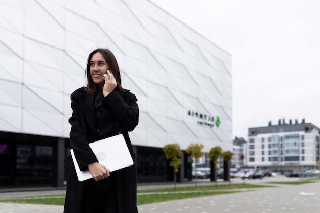 Young adult woman talking on the phone on the background of the university