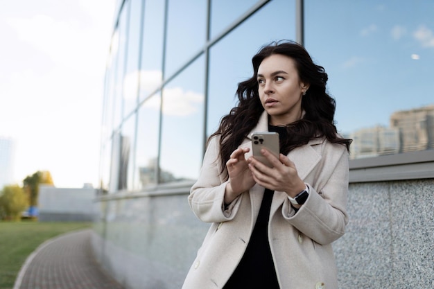 Young adult woman with a phone in her hands on the background of the university