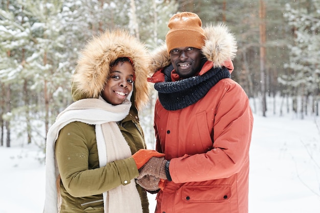 Young affectionate african american couple in winterwear holding by hands