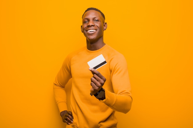 Young african american black man against orange wall, money concept.