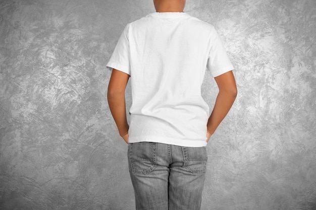 Young African American boy in blank white tshirt standing against textured wall