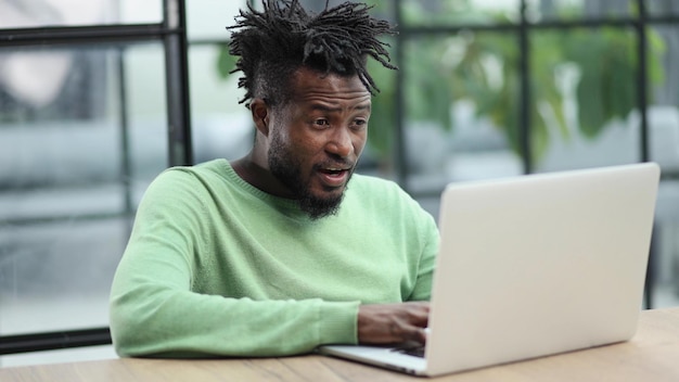 Young african american business man sitting in loft office or cafe working on new online it startup