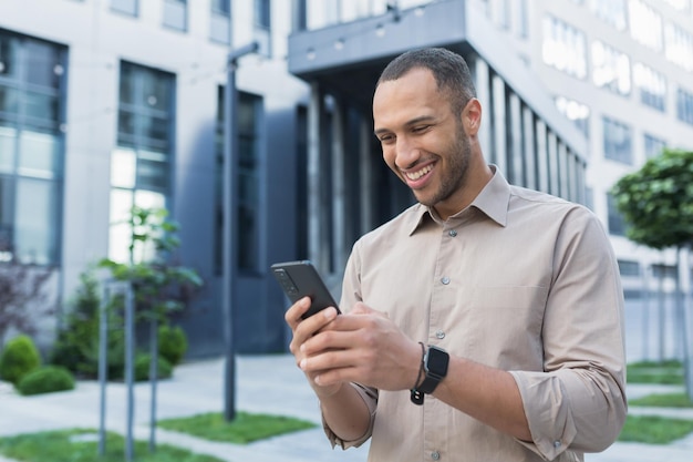 Young african american businessman using smartphone smiling and happy typing message online man