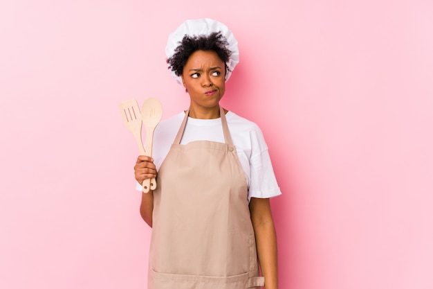 Young african american cook woman confused, feels doubtful and unsure.