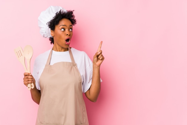 Young african american cook woman pointing to the side