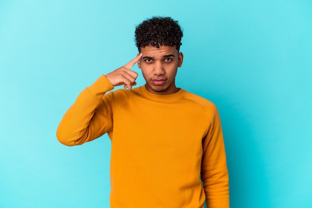 Young african american curly man isolated on blue pointing temple with finger, thinking, focused on a task.