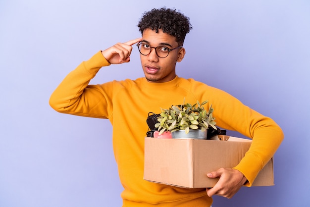 Young african american curly man isolated moving to a new home pointing temple with finger, thinking, focused on a task.