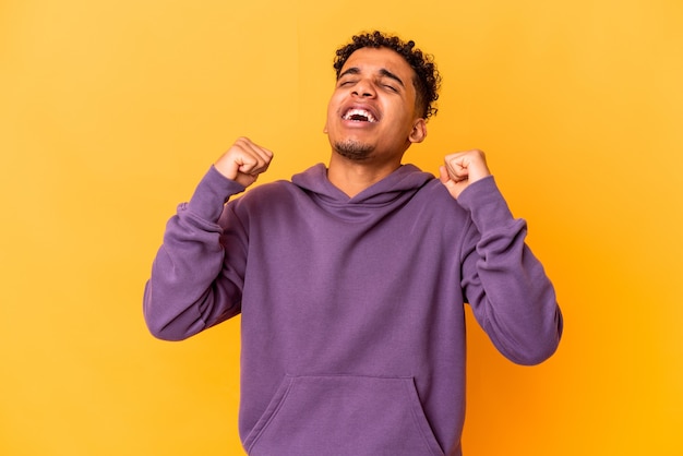 Young african american curly man on yellow celebrating a victory, passion and enthusiasm, happy expression.