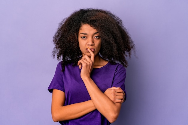 Young african american curly woman isolated on purple background unhappy looking in camera with sarcastic expression.