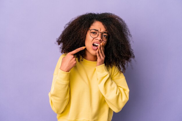 Young african american curly woman isolated on purple wall having a strong teeth pain, molar ache.