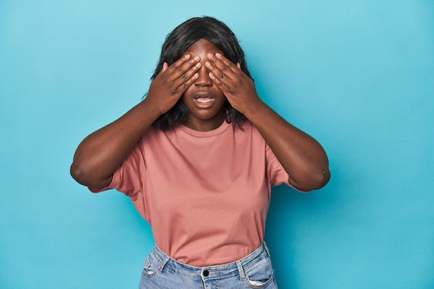 Young african american curvy woman afraid covering eyes with hands