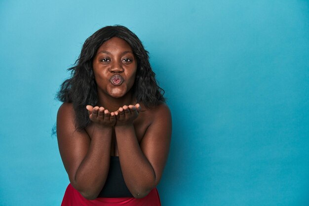 Young african american curvy woman folding lips and holding palms to send air kiss