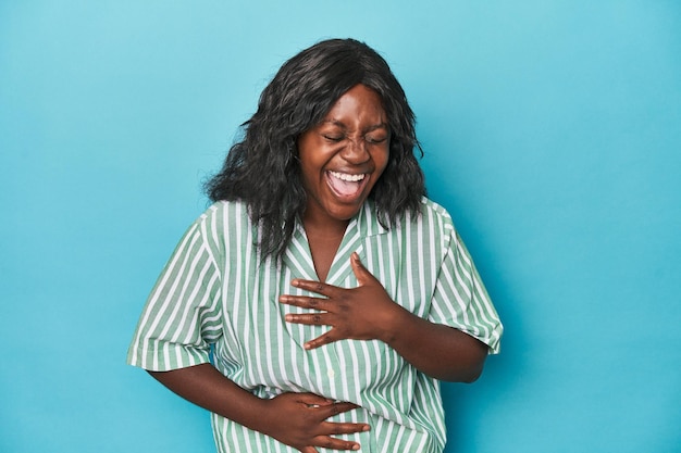 Young african american curvy woman laughs happily and has fun keeping hands on stomach