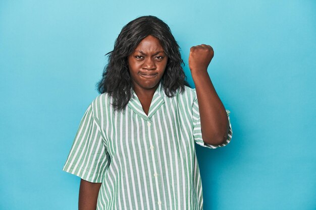 Young african american curvy woman showing fist to camera aggressive facial expression