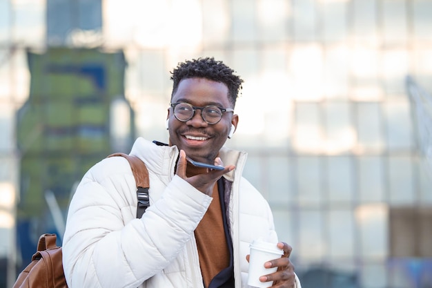 Young African American entrepreneur business man holding coffee in cardboard cup and talking on phone