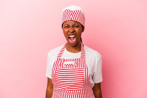 Young african american ice cream maker woman isolated on pink background screaming very angry and aggressive.