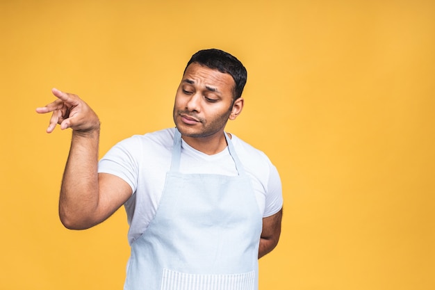 Young african american indian black cooker man wearing apron isolated over yellow background.