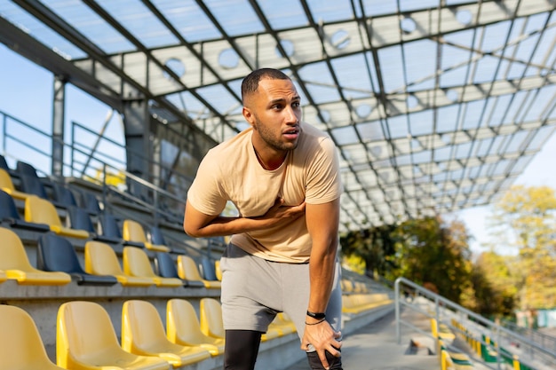 Young african american male sportsman athlete runner tired after training he is standing in the